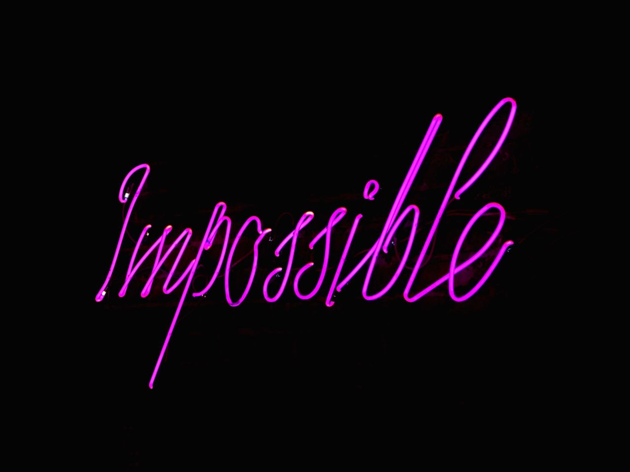Eye-catching neon Impossible sign glowing against a dark backdrop, perfect for inspirational themes.